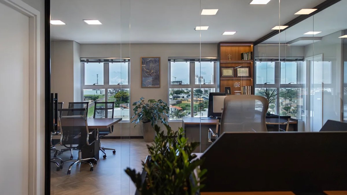 Sala de reunião do escritório da Saggin Advocacia, com mesa e cadeiras junto às janelas