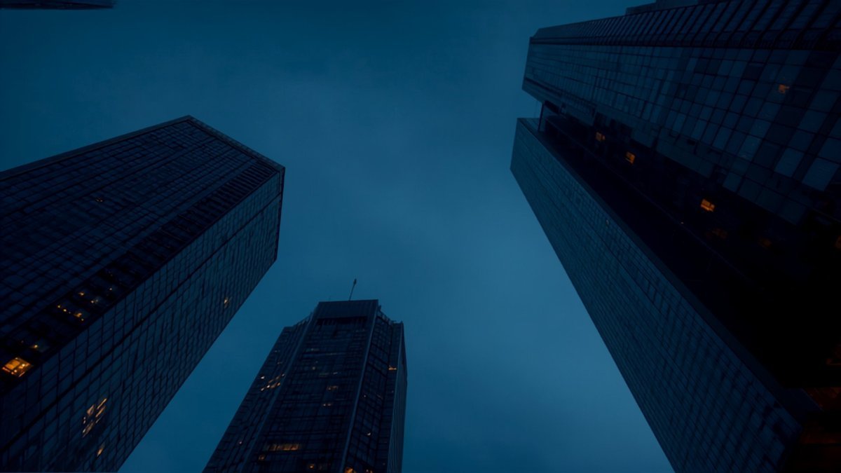 Torres de vidro de um centro financeiro vistas de baixo, na hora azul do anoitecer